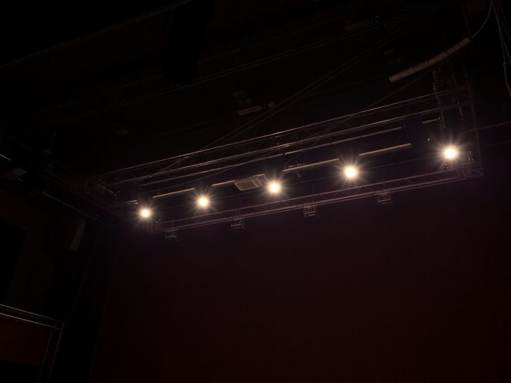 Scenă de teatru iluminată, echipament tehnic vizibil.