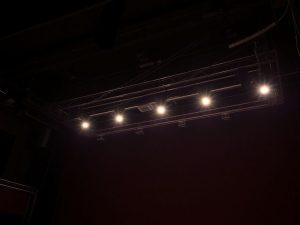 Scenă de teatru iluminată, echipament tehnic vizibil.