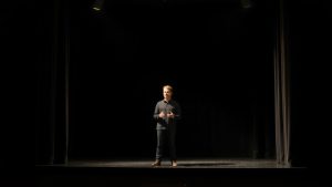 Actor solitar pe scenă, luminat dramatic, monolog teatral.